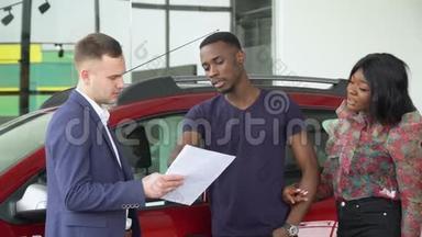 年轻英俊的<strong>汽车销售</strong>商向他在汽车经销店的非裔美国顾客解释了一些事情。 汽车生意，汽车